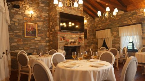 un restaurante con mesas y sillas blancas y chimenea en Domatia Stone Hotel, en Soke
