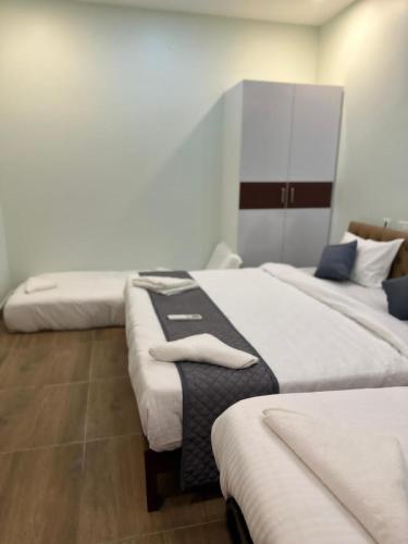 a room with three beds with white sheets at Serene Villa in Puducherry
