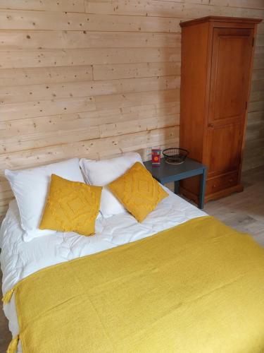 a bedroom with a bed with yellow sheets and a table at Petit studio dans la prairie in Saint-Auban