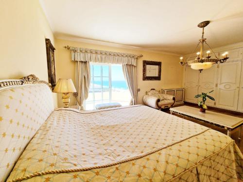 1 dormitorio con 1 cama grande y ventana grande en Praia Grande Guest House en Colares