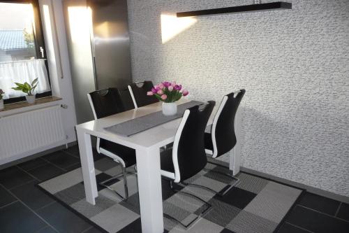a white dining room table with black chairs and flowers at Appartement 2 Schlafzimmer, Terrasse, Hund, Kamin in Bodenwerder