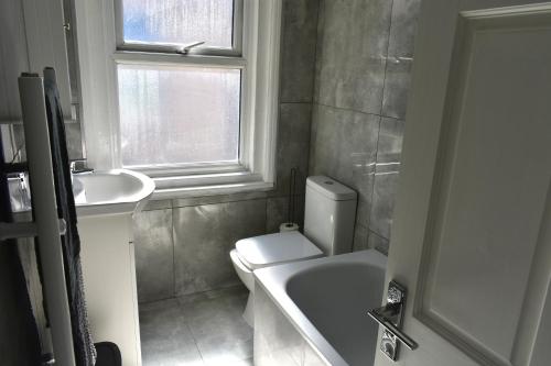 a bathroom with a toilet and a sink and a window at Seaside Flat, Contractors, Family, Business, Parking in Portslade