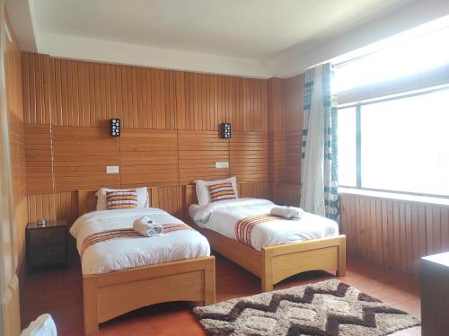 una camera con due letti e una finestra di Hotel Tayatha a Tawang