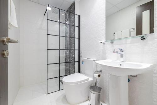 a white bathroom with a toilet and a sink at Elegant Studio with Pool View and Great Facilities in Dubai