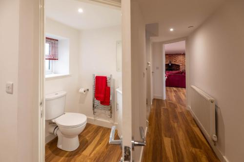een witte badkamer met een toilet en een hal bij Cariad - Spacious 3 bed, group getaway Luxury Cottage with Private Hot Tub in Denbigh