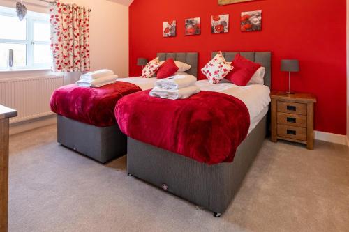 twee bedden in een slaapkamer met rode muren bij Cariad - Spacious 3 bed, group getaway Luxury Cottage with Private Hot Tub in Denbigh