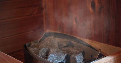 a tub filled with rocks in a wooden room at Fandina細原,北欧サウナと露天風呂を満喫,ルクルーゼの鍋と食器で統一されたカジュアルヴィラ in Kita-karuizawa