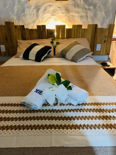 a large bed with two pillows and flowers on it at Chalés XIÉ in São Miguel dos Milagres