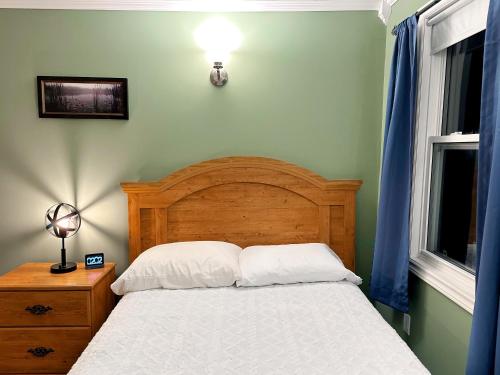 Normans CovePort suite @ The Homestead Oceanfront的一间卧室配有一张带木制床头板的床和两个窗户。