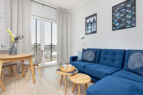 Business Center Apartments Warsaw Wola by Renters في وارسو: غرفة معيشة مع أريكة زرقاء وطاولة