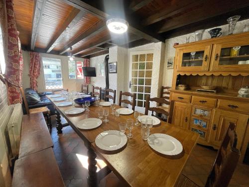 d'une salle à manger avec une grande table, des assiettes et des verres dans l'établissement Cotterg Rez - Appartement dans chalet, à La Clusaz