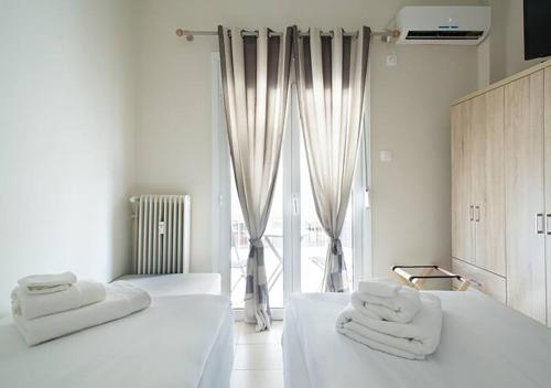 Habitación blanca con 2 camas y toallas. en MEDLUXE EASY ACROPOLIS APARTMENT!, en Atenas