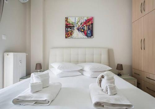 Un dormitorio con una cama blanca con toallas. en MEDLUXE EASY ACROPOLIS APARTMENT! en Atenas