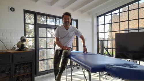 a man sitting on a bed in a room with windows at LA CASITA in Buenos Aires