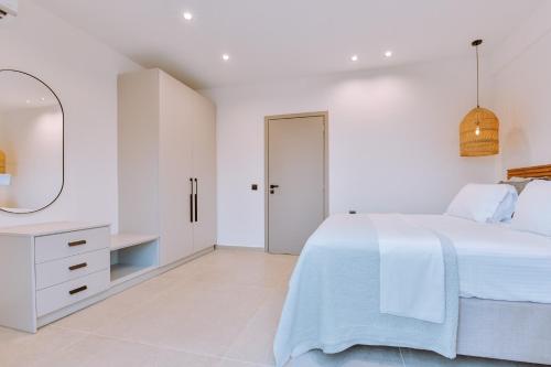 a white bedroom with a bed and a mirror at MiLiON RESIDENCES in Parga