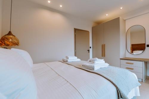 a white bedroom with a large bed and a mirror at MiLiON RESIDENCES in Parga