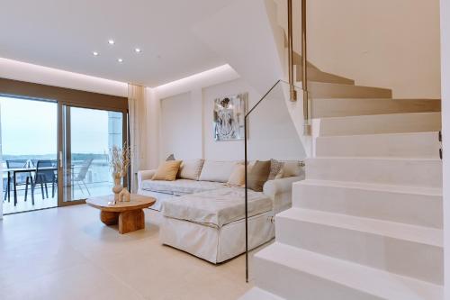 Sala de estar blanca con escaleras y sofá en MiLiON RESIDENCES, en Parga
