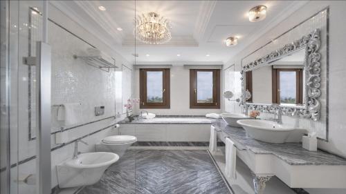 Royal Suite at The San Roque Club في سان روكي: حمام ابيض بثلاث مغاسل وحوض استحمام