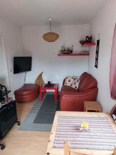 sala de estar con sofá rojo y mesa en OSTSEEFERIEN IN LICHTENHAGEN-DORF FERIENWOHNUNG, en Elmenhorst Anteil