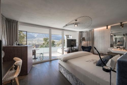 a bedroom with a bed and a desk and a balcony at Preidlhof Luxury Dolce Vita Resort in Naturno