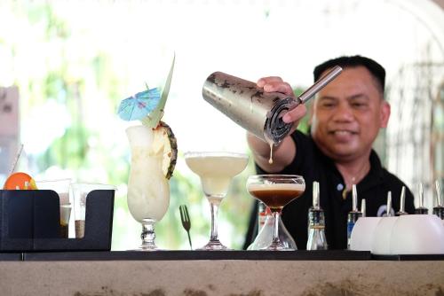 a man pouring a drink into two martini glasses at Mad Monkey Dumaguete in Dumaguete