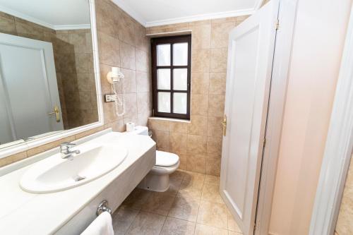 a bathroom with a sink and a toilet and a mirror at Hotel Restaurante De Torres in Felechosa