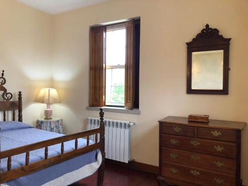 a bedroom with a bed and a dresser and a window at Casa das Eiras in Tondela