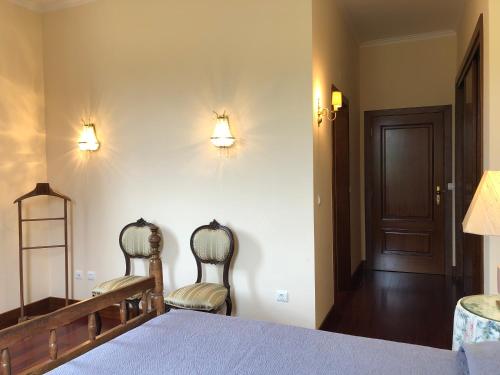 a bedroom with a bed and two chairs and a door at Casa das Eiras in Tondela