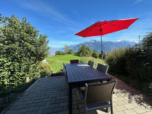 a wooden table with a red umbrella on a patio at Mirador Lodge - Crans Montana - Swiss Alps in Crans-Montana