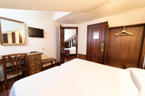 a bedroom with a bed and a desk and a television at Hotel Restaurante De Torres in Felechosa