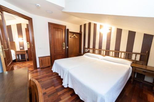 a bedroom with a white bed and striped walls at Hotel Restaurante De Torres in Felechosa