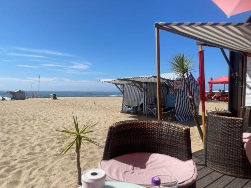 una playa con una silla y una mesa en la arena en Spacieux Appartement à Porto en bord mer, en Póvoa de Varzim