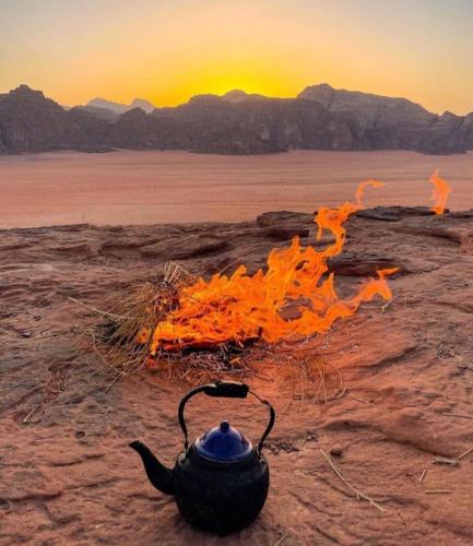 a tea pot sitting on the ground with a fire at Wadi Rum Calma camp in Aqaba