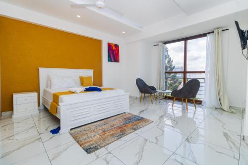 een slaapkamer met een bed en stoelen en een gele muur bij Luxury 3br Ensuite Apt in Prestigious Nyali in Mombasa
