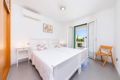 um quarto branco com uma cama, uma secretária e uma janela em Can Roig Loft em Colonia de Sant Pere