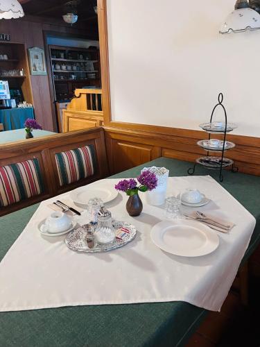 a table with plates and silverware on a white table cloth at Athecada Frühstückspension in Birkfeld