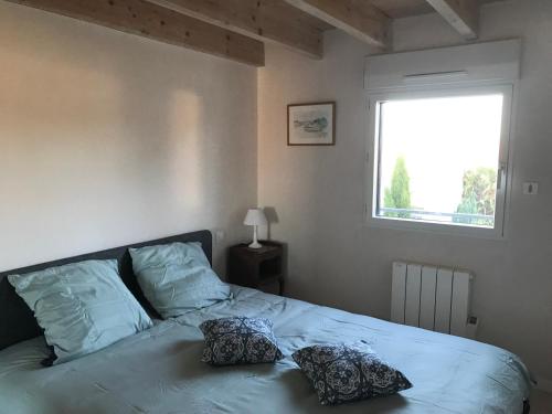 1 dormitorio con 1 cama con 2 almohadas en Les PECHERS N 2 MAISON DE 87 m2 à 5mn de La Rochelle de l'île de ré et des plages, en La Genilliere