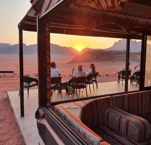 a group of people sitting at tables in the desert at Wadi Rum Calma camp in Aqaba