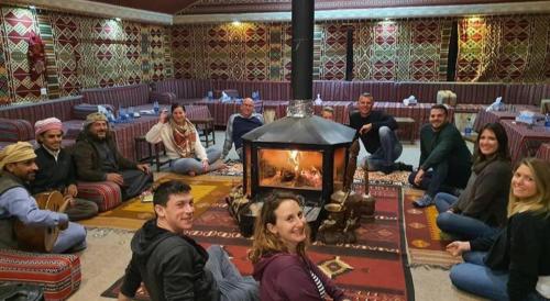 a group of people sitting in a room with a fireplace at Wadi Rum Calma camp in Aqaba