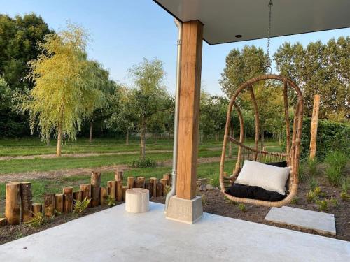 a swing set in a park with a field at Stijlvol huisje met veranda! Tuynloodz C in Beers