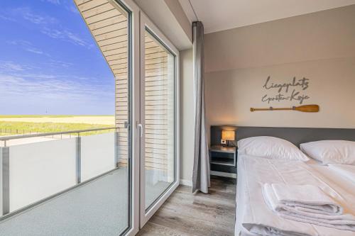 ein Schlafzimmer mit einem Balkon mit einem Bett und einem Fenster in der Unterkunft Gersten-Koje in Büsum