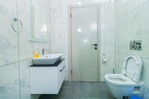 a white bathroom with a toilet and a sink at Luxury 3br Ensuite Apt in Prestigious Nyali in Mombasa
