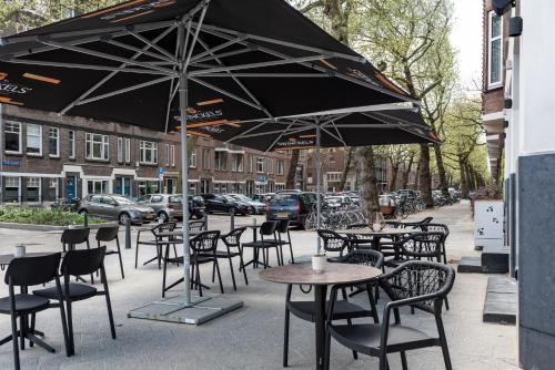 an outdoor cafe with tables and chairs and an umbrella at Le Marin Hotel Rotterdam City - Handwritten Collection in Rotterdam