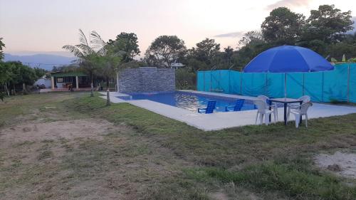 a swimming pool with a table and an umbrella at Casa de campo para 10 personas in Ibagué