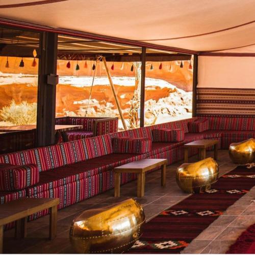 a room with red couches and gold tables and benches at Wadi Rum Calma camp in Aqaba