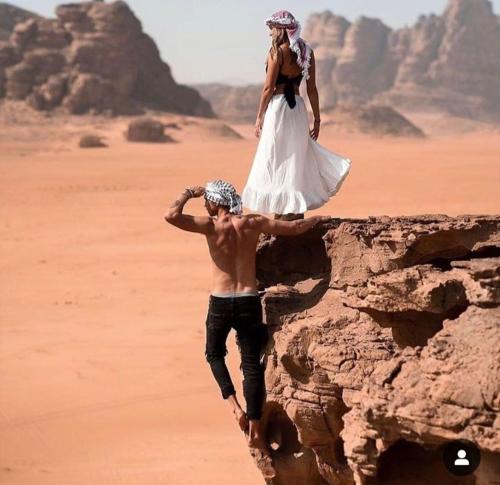 a man and a woman standing on a rock in the desert at Wadi Rum Calma camp in Aqaba