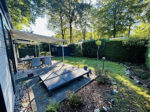 a backyard with a wooden table and a patio with a tent at Vakantiepark Klein Vink - 198 in Arcen