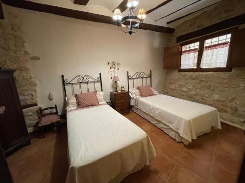 a bedroom with two beds and a stone wall at Casa Lidia - Antigua Posada Real in Valderrobres