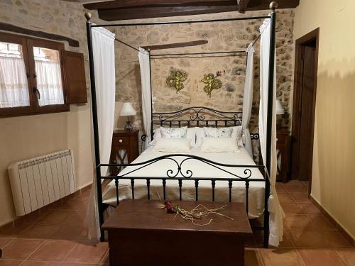 a bedroom with a metal canopy bed with a wooden table at Casa Lidia - Antigua Posada Real in Valderrobres