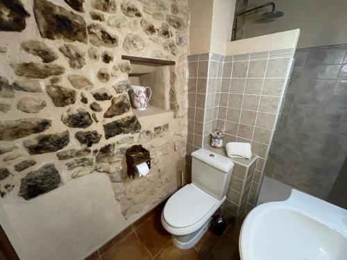 a bathroom with a white toilet and a stone wall at Casa Lidia - Antigua Posada Real in Valderrobres